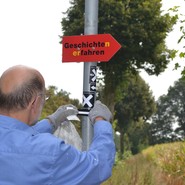WHB-Wegezeichner Ulrich Buntrock bringt einen MAX-Aufkleber an (Foto: WHB/U: Steinkrüger). (vergrößerte Bildansicht wird geöffnet)